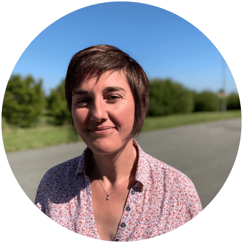 Christelle, responsable planning de l'équipe Stan.bio, souriante en chemise fleurie rose et blanche, photographiée en plein air par beau temps
