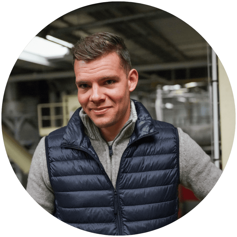 Jules, responsable production chez Stan.bio, souriant en gilet matelassé bleu marine, photographié dans les locaux de fabrication